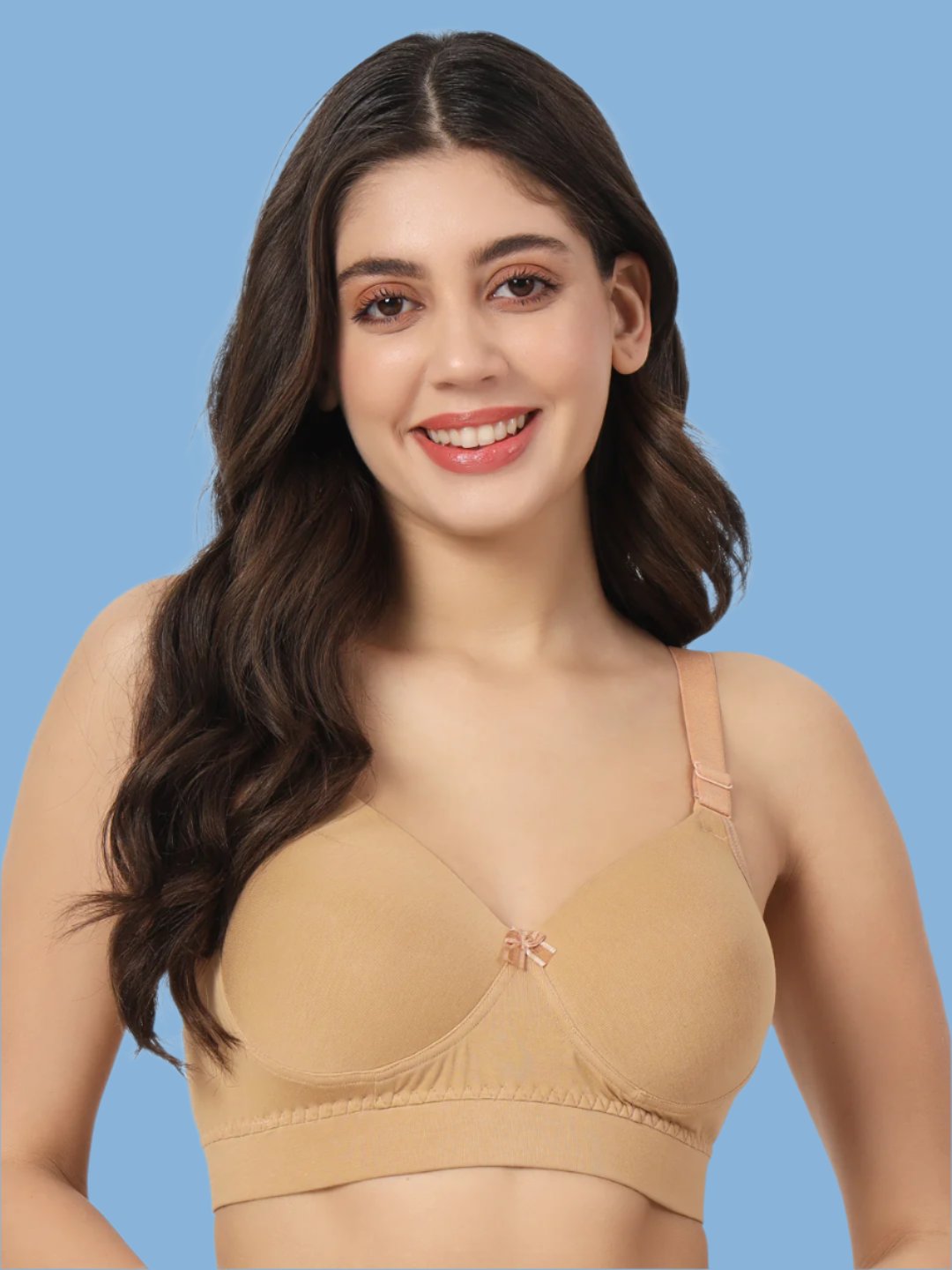 A woman wearing a beige, full coverage, padded bra with adjustable straps.